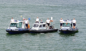 3 policyjne łodzie na jeziorze stoją obok siebie w nich policjanci