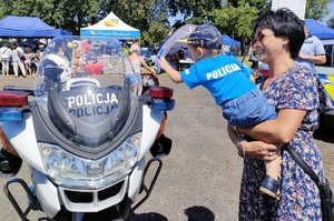 przy policyjnym motocyklu stoi kobieta z dzieckiem