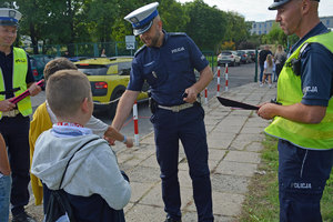 policjanci rozdają odblaski uczniom w pierwszym dniu ich szkoły
