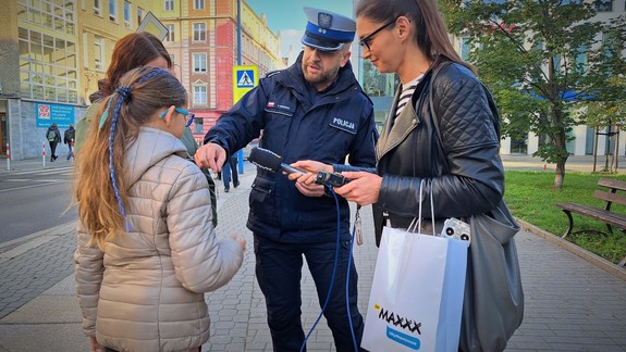 policjant rozdaje odblaski wraz reporterką Radia RMF MAXXX