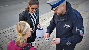policjant rozdaje odblaski wraz reporterką Radia RMF MAXXX