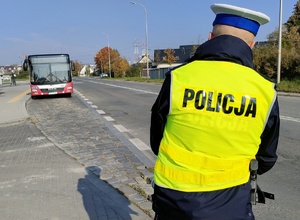 policjant stoi przy ulicy w tle autobus