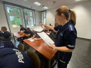 policjantka rozdaje testy wiedzy policjantom biorącym udział  w zawodach