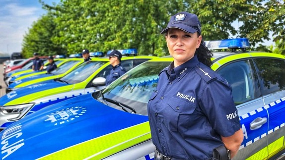 Zdjęcie przedstawia policjantkę na tle nowych radiowozów.