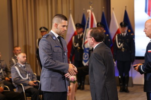 policjant odbiera medal z rąk komendanta i ministra