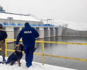 policjant z psem stoi przy rzece
