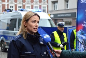 Zdjęcie przedstawia policjantkę w trakcie rozmowy z mediami.