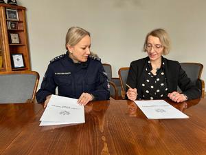 Zdjęcie przedstawia dwie kobiety siedzące przy biurku.