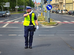 policjant na skrzyżowaniu kierunkuje ruchem