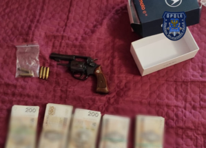 Zdjęcie przedstawia broń, obok leżą banknoty i amunicja.