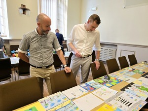 Zdjęcie przedstawia komisję konkursową podczas wybierania prac.