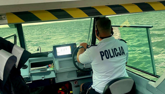 policjant za sterami łodzi policyjnej