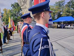 policjanci ze sztandarem na placu przed pomnikiem