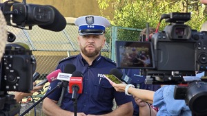 policjant przed mikrofonami udziela informacji