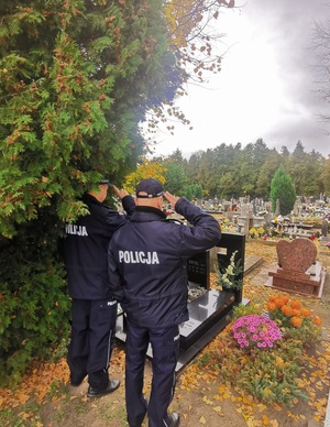 Zdjęcie przedstawia policjanta na cmentarzu.