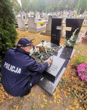 Zdjęcie przedstawia policjanta na cmentarzu.