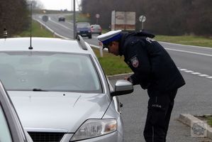 policjant pochyla się nad kierowcą siedzącym w samochodzie