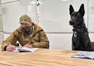 Zdjęcie przedstawia psa z policjantem.