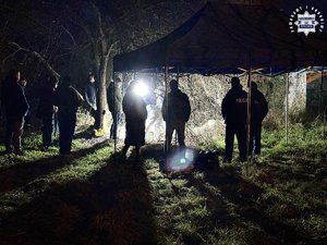 Zdjęcie przedstawia stojących mężczyzn, jeden z nich jest w białym kombinezonie.