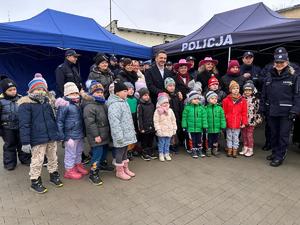 Zdjęcie przedstawia dzieci, obok nich stoją policjanci.