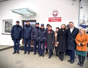 Zdjęcie przedstawia grupę ludzi na tle budynku, wśród nich policjanci.