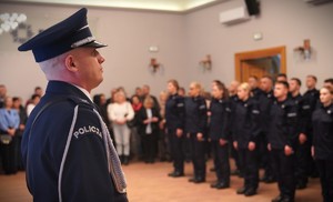 Zdjęcie przedstawia policjanta w czapce na pierwszym tle.