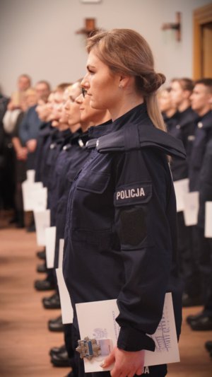 Zdjęcie przedstawia policjnatkę stojącą z rozkazem.