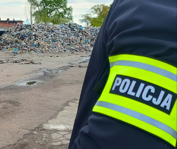 Wysypisko śmieci, na pierwszym planie policjant.