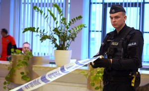 Policjant rozwija taśmę policyjną.