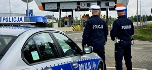 Zdjęcie przedstawia policjantów stojących na auto stradzie A4, przy nich radiowóz.