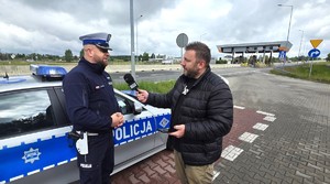 Zdjęcie przedstawia policjanta rozmawiającego z dziennikarzem.