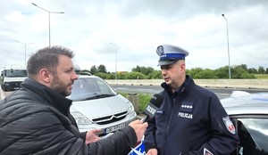 Zdjęcie przedstawia policjanta rozmawiającego z dziennikarzem.