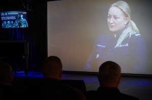 Kobieta w mundurze na ekranie.