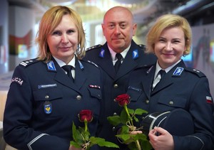 Kobiety, z różami, za nimi mężczyzna.
