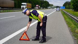 Policjant ustawia trójkąt bezpieczeństwa na autostradzie.