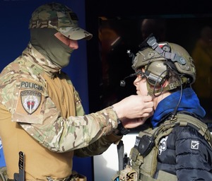 Policjant pomaga ubrać policyjny sprzęt.