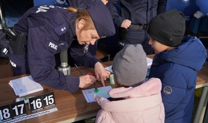Policjantka zbiera odciski palców dzieciom.