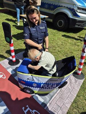 Policjantka, obok niej dziecko w radiowozie.