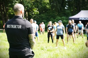 Mężczyzna z koszulką z napisem &amp;quot;Instruktor&amp;quot; stoi przed grupą.