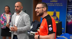 Ratownik medyczny, obok niego mężczyzna w garniturze.