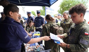 Policjantka wręcza ulotkę uczniowi.