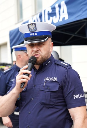 Policjant mówi do mikrofonu.