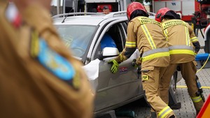 Strażacy rozcinają auto.