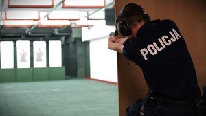 Policjant strzela zza przesłony.