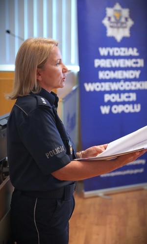 Policjantka trzyma w ręku kartki,