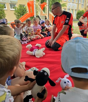 policjant podczas instruktażu dla dzieci z pierwszej pomocy