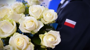 Zdjęcie: białe róże, obok flaga biało-czerwona.