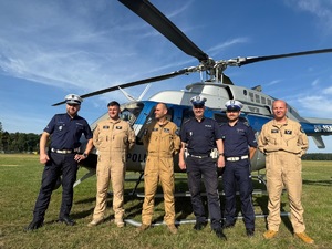 Zdjęcie przedstawia policjantów, w tle helikopter.