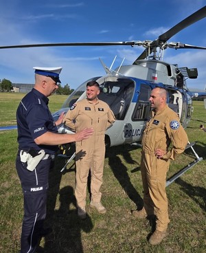 Policjanci rozmawiają przy helikopterze.