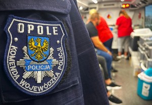 naszywka na ramię,na mundur, w tle krwiobus i osoby zajmujące się pobieraniem krwi